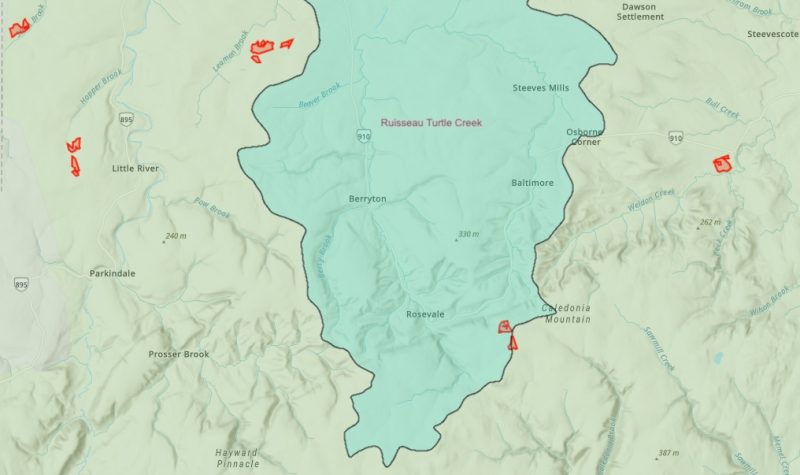 A map shows the contours of a watershed in blue. Red areas both inside and outside the watershed show places where herbicide spraying is permitted by the provincial government.