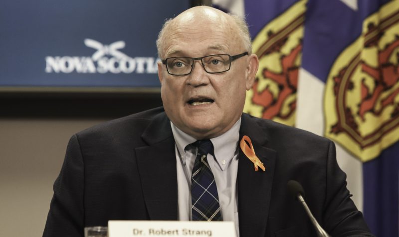 A man sits at a desk speaking through a microphone