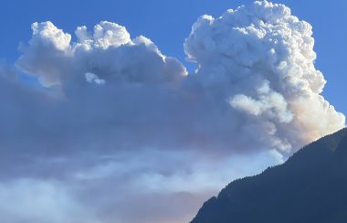 wildfire smoke rises over a mountain.