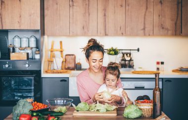Une femme s'amusant avec sa fille tout en préparant une salade dans la cuisine. (Photo: Nicolas)