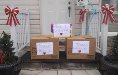 Brown boxes with white paper with text on a porch.