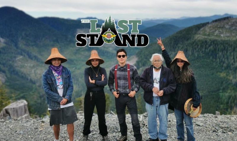 Five Indigenous people stand in front of a green valley