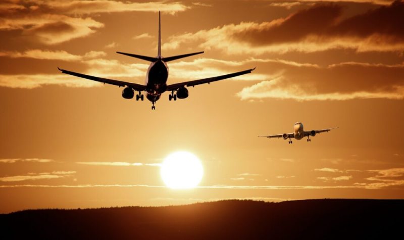 Image de la silhouette de deux avions en plein vol vers un soleil couchant.