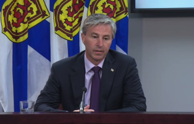 A man sitting at a desk speaks into a microphone