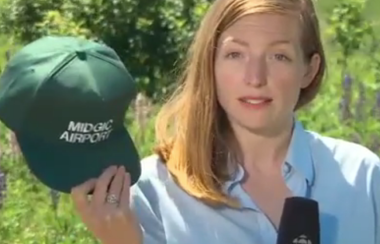 Woman holding a microphone and hat that says Migdic Airport.