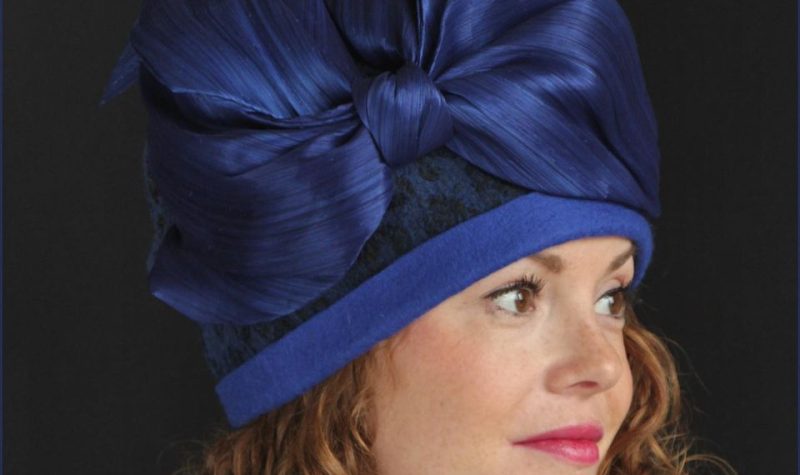Une femme portant un chapeau bleu foncé muni d'une grosse boucle