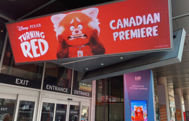 A red screen with a red panda displayed on top of a set of doors on a large theatre.