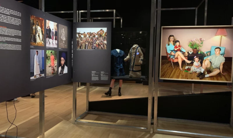 Du côté gauche se trouve des une collection de toiles d'artistes queer. À droite, une plus grande toile affiche une mère et ses enfants dans un cadre familial traditionnel.