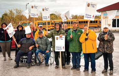 Pictured are the bus drivers standing with signs in front of a number of school buses.