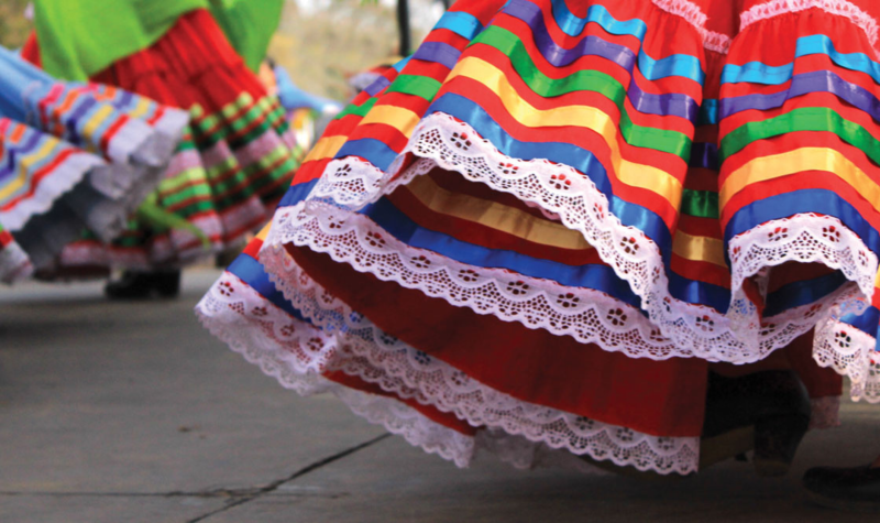 Colourful dresses and heels dance on a tarmac.