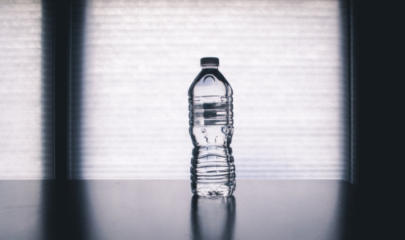 A photo of standstill of a plastic water bottle sits on a table.