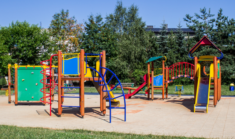 A rainbow coloured playground gleams in the afternoon sunlight.