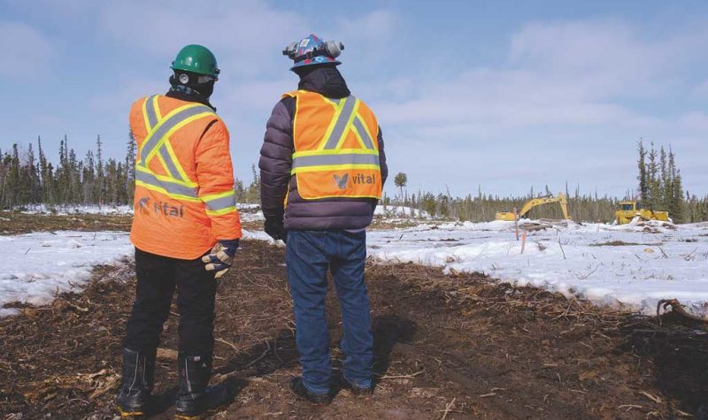 Deux travailleurs miniers observent un chantier, en hiver.