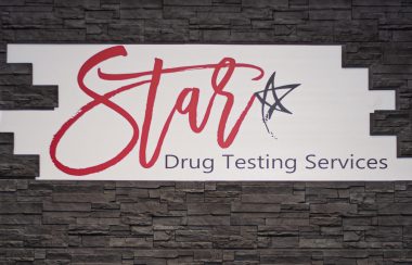 Bannière blanche sur un mur noir de la clinique Star Drug Testing