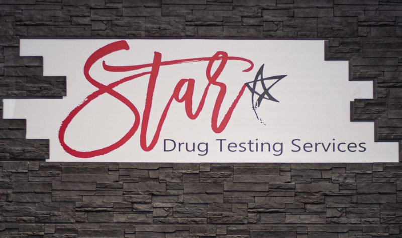 Bannière blanche sur un mur noir de la clinique Star Drug Testing