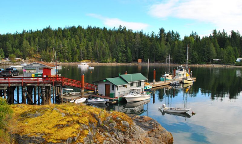 Boats are moored at a dock and on floats in a BC coastal community.