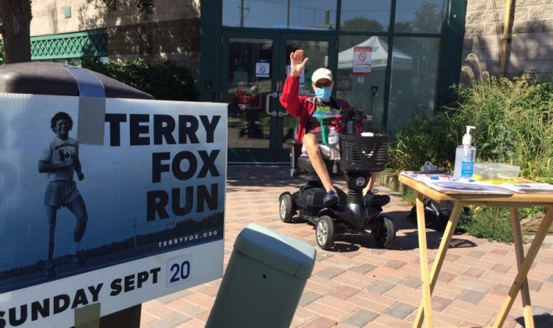 Will Dwyer envois la main à l'extérieur derrière une pancarte de Tery Fox