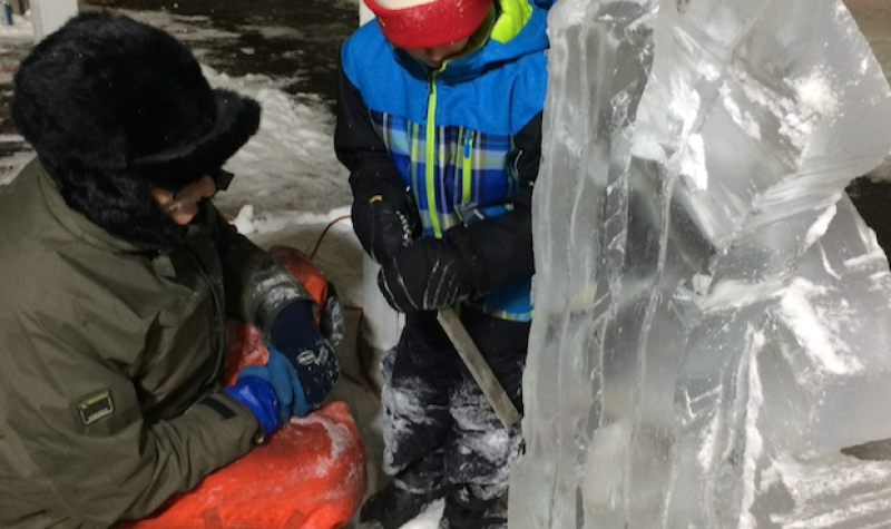 A young boy helps ice sculptor Richard Chaisson with his work in Winterfest 2019. Image: Sackville.com