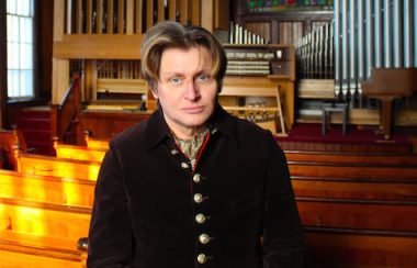 Xaver Varnus stands with his newly installed pipe organ in a church