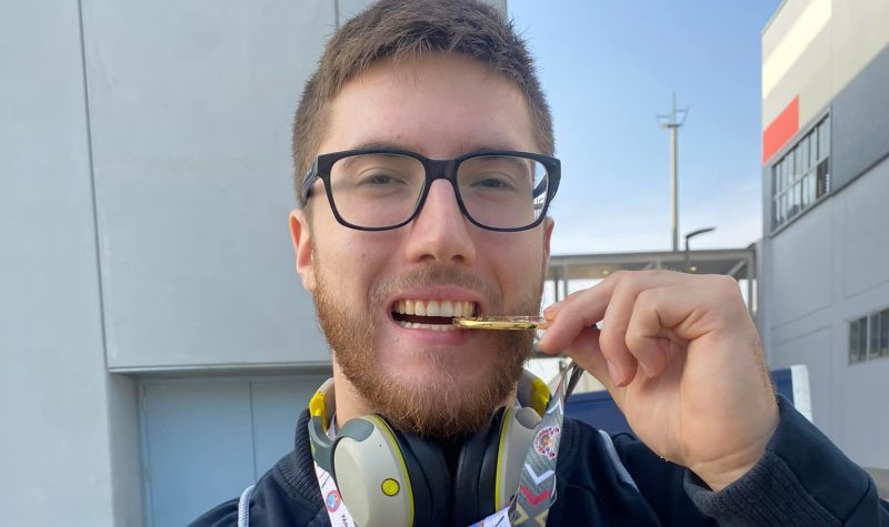 A young man with glasses bites down on a gold medal from the Junior Pan-American Championships.