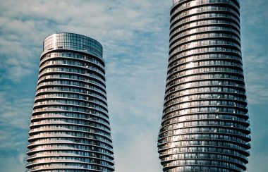 Two silver cylinder buildings against a blue, cloudy sky.