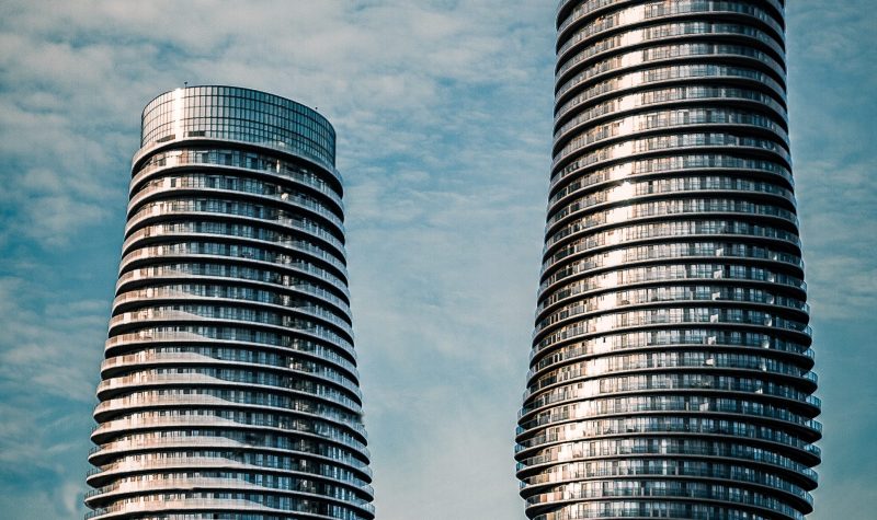 Two silver cylinder buildings against a blue, cloudy sky.