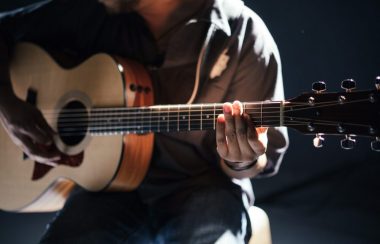 Une personne assise tient une guitare.