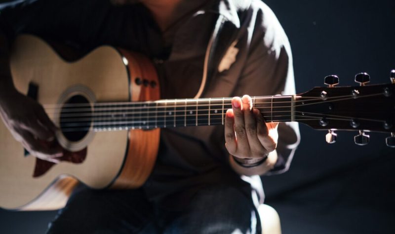 Une personne assise tient une guitare.