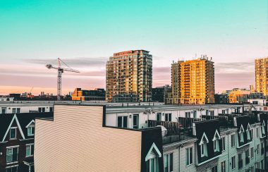 A set of buildings with a crane in the background in a city.