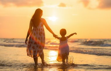 Une maman et une fille se tenant la main sur la plage