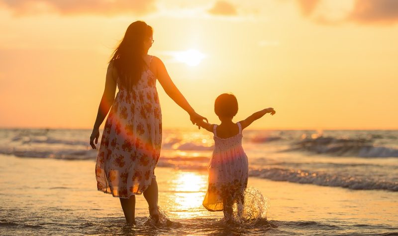 Une maman et une fille se tenant la main sur la plage