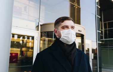 Un homme portant le masque devant un bâtiment
