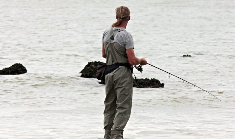 Un homme debout sur le bord de l'eau avec une canne à pêche en main