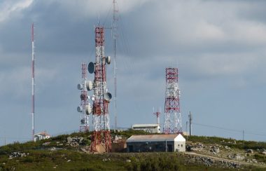 Trois antennes sur le haut d'une côte à côté d'un bâtiment