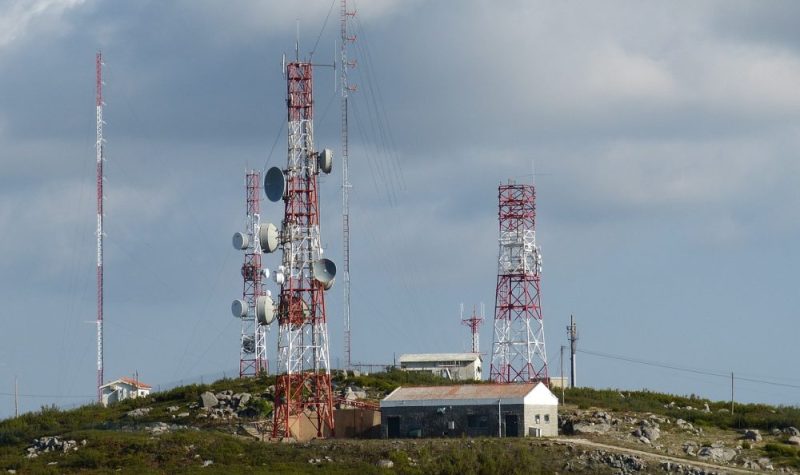 Trois antennes sur le haut d'une côte à côté d'un bâtiment