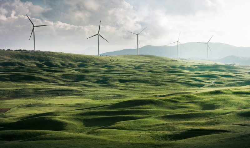 A photo of wind turbines surrounded by grass on a hill