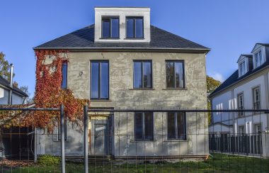 Une maison abandonnée en bord de rue, le ciel est bleu.