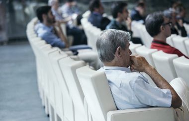 Des gens assis sur des fauteuils blancs attentifs devant eux