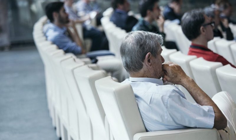 Des gens assis sur des fauteuils blancs attentifs devant eux