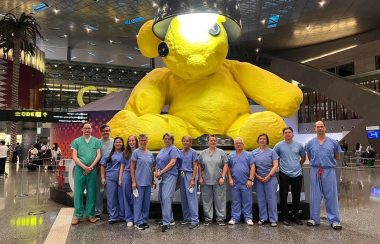 Photo of about 30 healthcare workers from Dalhousie University at the airport in scrubs ready to perform surgery in Rwanda.