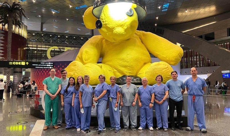 Photo of about 30 healthcare workers from Dalhousie University at the airport in scrubs ready to perform surgery in Rwanda.