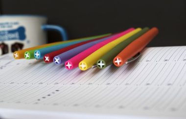 Un cahier avec des crayons de couleur et une tasse en arrière-plan