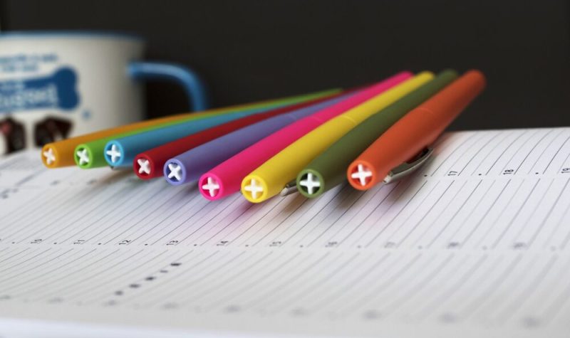 Un cahier avec des crayons de couleur et une tasse en arrière-plan