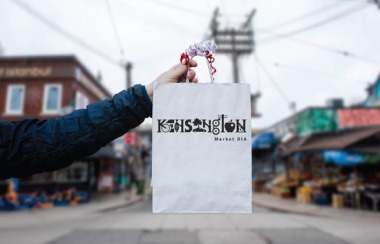 A person with a blue sleeve holding a white bag outside on a city street