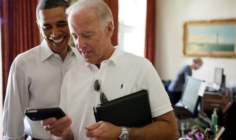Joe Biden regarde un écran de téléphone en compagnie de Barack Obama