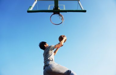 Un jeune homme qui est sur le point de marquer un but au basketball.