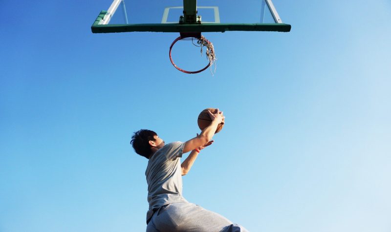 Un jeune homme qui est sur le point de marquer un but au basketball.