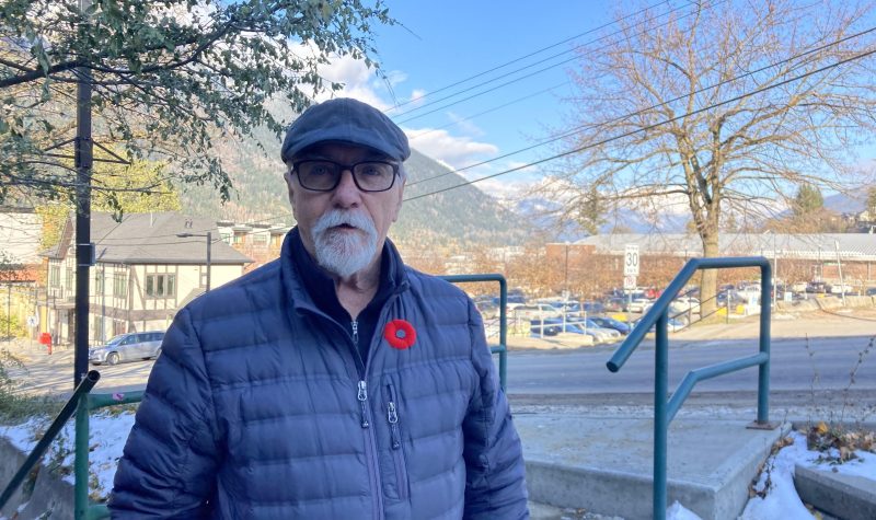 Bill Haire, branch president of the nelson branch of the royal canadian legion poses for an outdoor photo with nelson's elephant mountain in the background. Haire is wearing a red poppy on his jacket