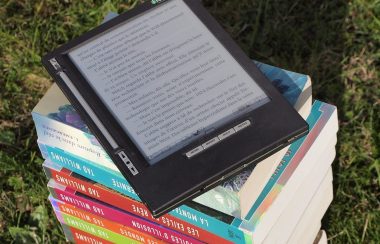 une tablette numérique poser sur des livres superposés.