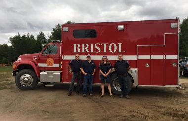 Four people standing in front of a fire equipment truck